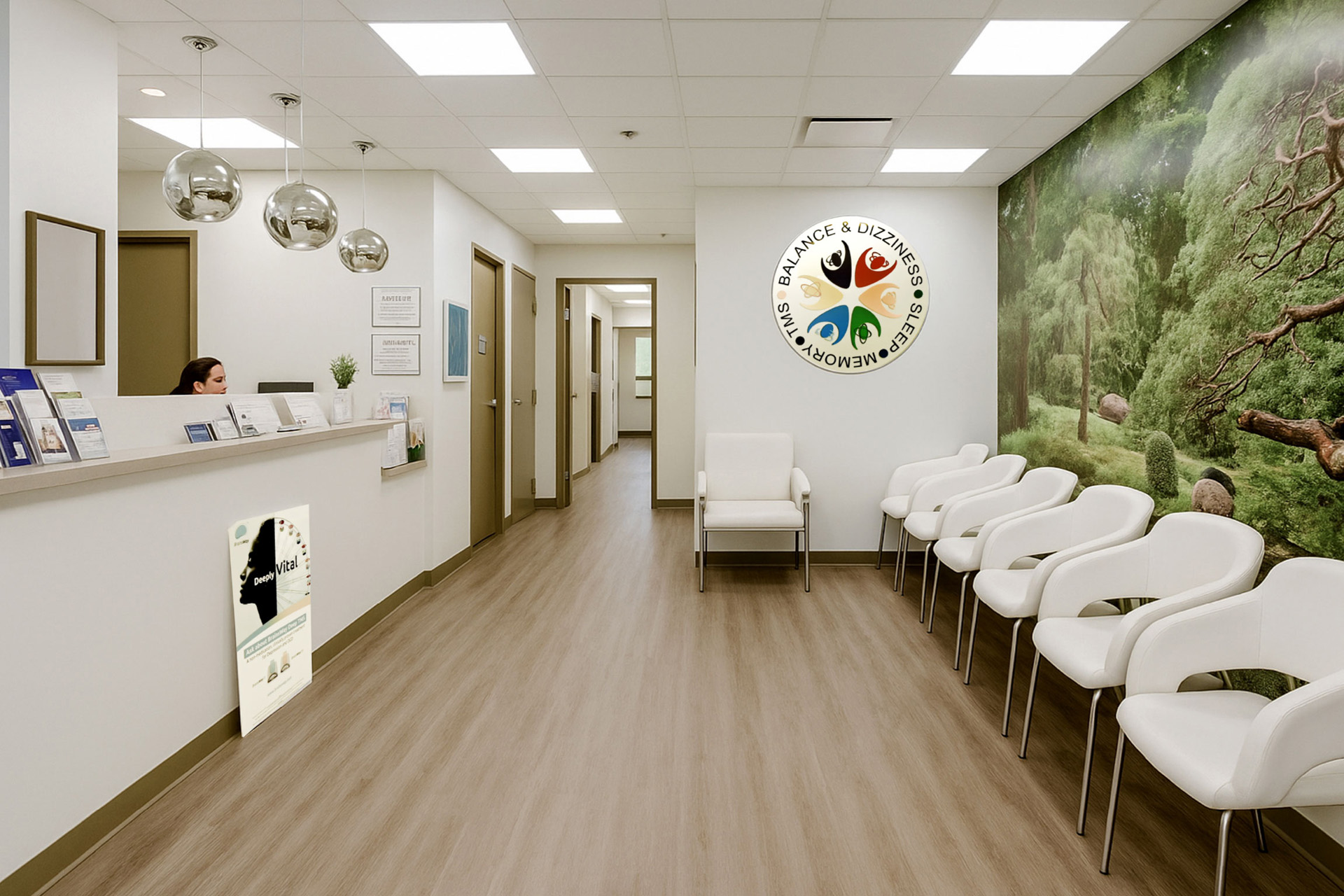 The image shows an interior space that appears to be a waiting area within a healthcare facility, featuring a reception desk with a logo, a wall-mounted sign with a tree and colorful leaves, and a row of chairs for seating.